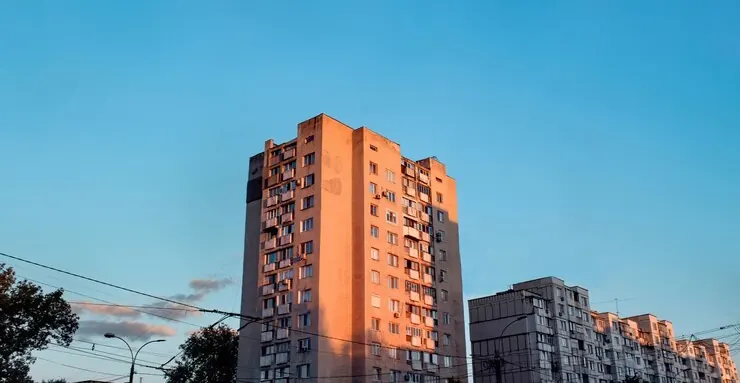 Tall residential blocks lit by the sun against a blue sky